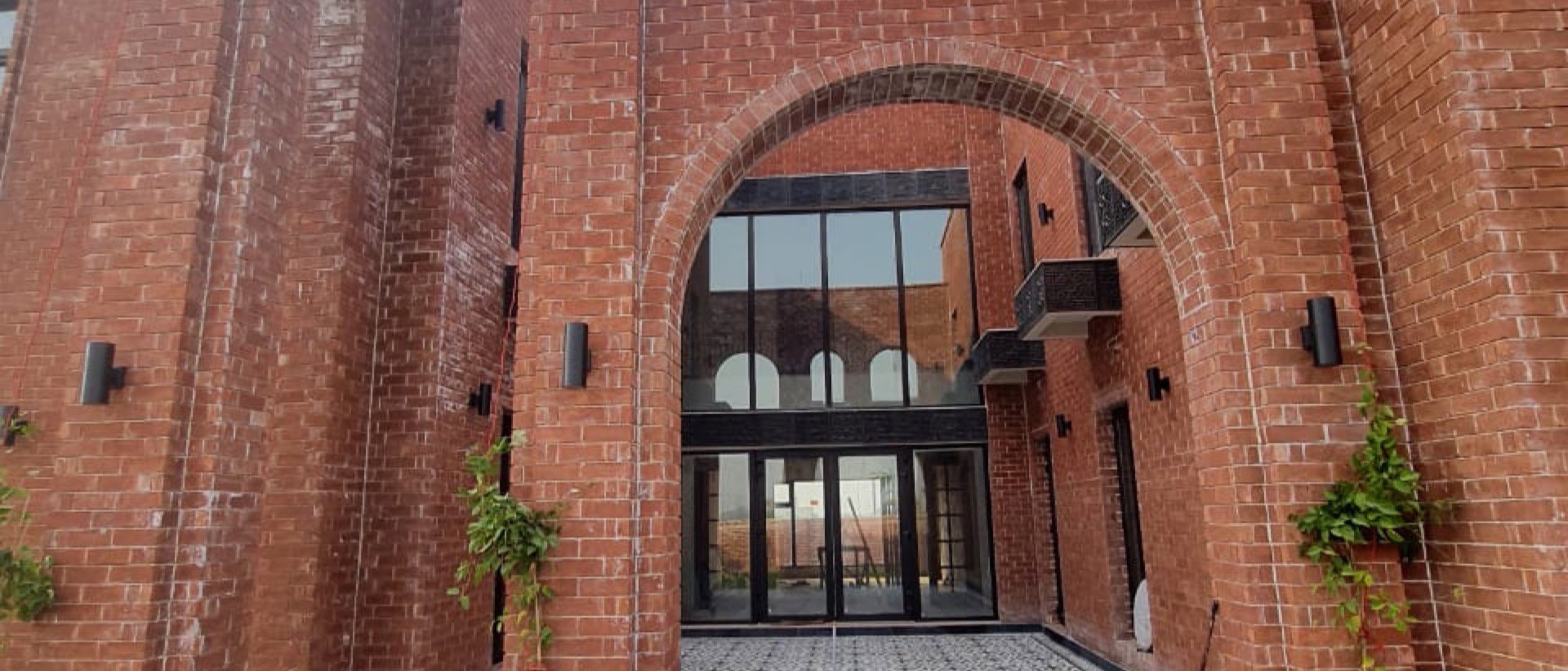 Brick villa with an arched entrance over a patterned tile courtyard